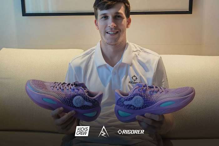 Austin Reaves holds purple and teal Rigorer sneakers.